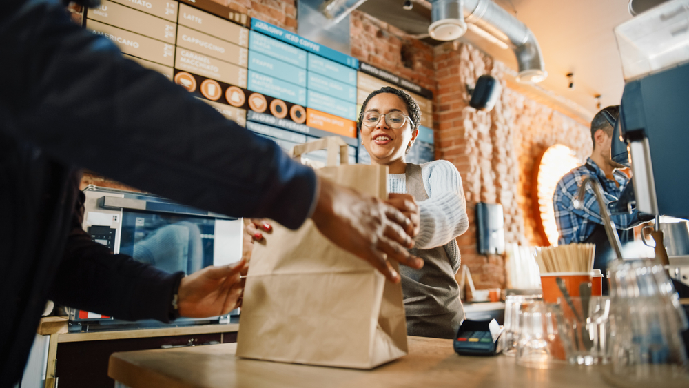 Restaurant server hands a to go bag to a customer