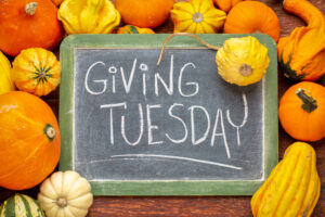 A chalkboard reads "Giving Tuesday" surrounded by pumpkins and fall decor